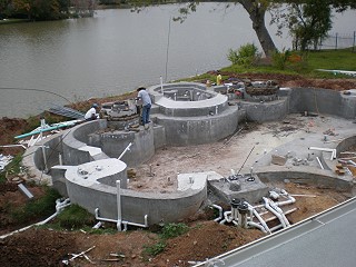 Swimming pool construction in progress with plumbing and concrete work underway.